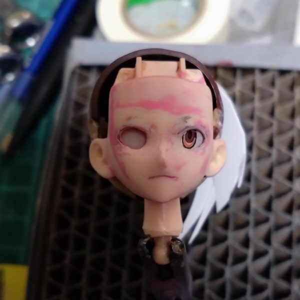 よくよく目的のキャラ画像見ながら目蓋周りの形をランナーくずと流し込み接着剤で少し変えてます。表面と形確かめるためにピンクサフ筆塗りしたりヤスったり、まつ毛ライン描いてみたりヤスったり。口周りも少し変更、輪郭も少しシャープにしてみてます。眼球パーツが中に入り過ぎなのでプラ板貼って厚み出し中です。硬化後顔パーツに合わせながら少しずつ修正かけます。Netflixで確認してみたら髪型の後側ばっちり出てたのでこれも今後修正とザックリ作った前髪ももう少し位置関係の調整で多分やり直し…まだまだ先は長そうです。（2枚目）