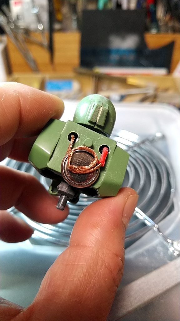 バックパックで隠れる位置に穴を開けて導線を貫通。ボタン電池を接続出来るようにする。ボタン電池の裏側にネオジウム磁石を瞬間接着剤で固定。ボタン電池のプラス極が磁力で固定されるので、その間に導線の片方を挟み込み、もう片方をマイナス極に接続出来るようにする。【最終的には導線を写真よりもっと細かく螺旋のバネ状にし、バックパックを取り付けることで電池に結線するようにしました。】