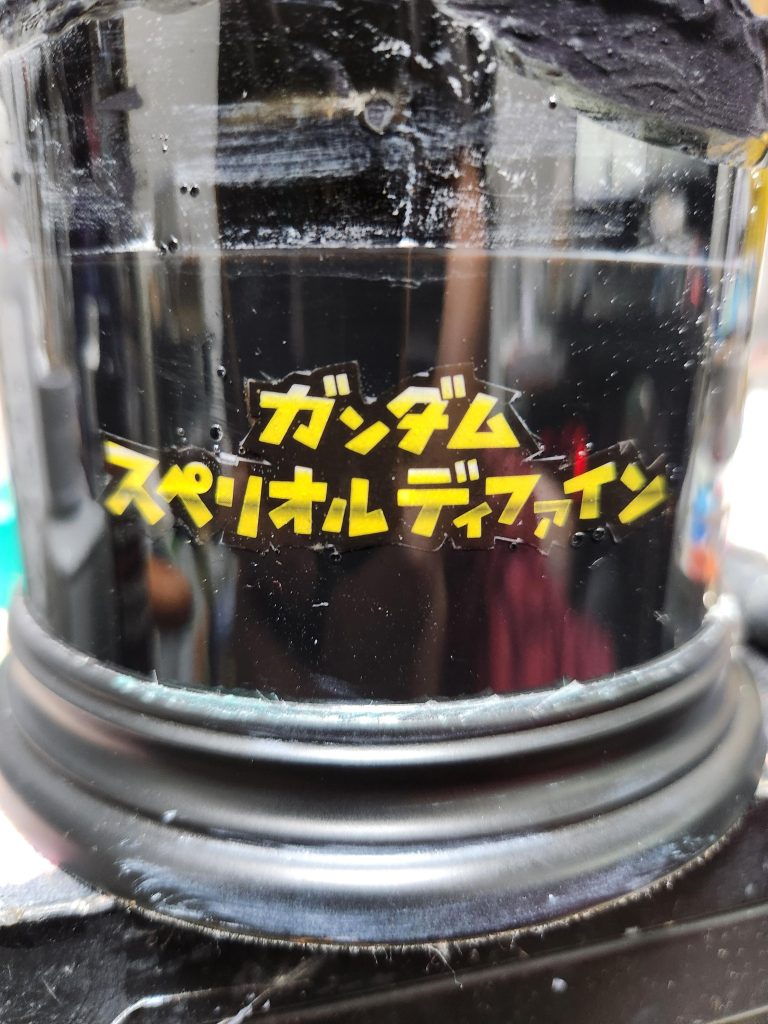 箱のロゴをハサミで切って両面テープ出はり、一緒にレジンでコーティング