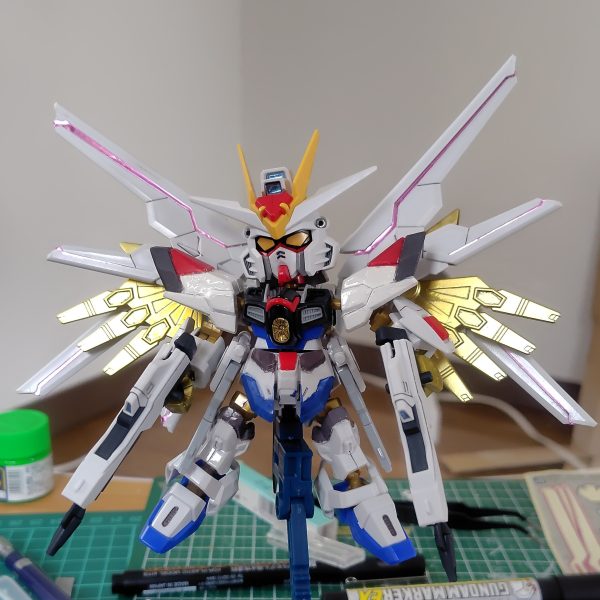 やっとここまで漕ぎ着けました。センサー類とウイングのラインは付属のホイルシールを使用。フロントアーマーに少々カラーアレンジを施しています。ビームライフルのブルーはおもちゃっぽくなるのであえてシールを貼っていません。ライフルはつや消し、それ以外は光沢のトップコートを吹いています。実はこれで完成ではなく、さらに一手間かけます。その前に肩パーツのポロリを改修せねば。（1枚目）