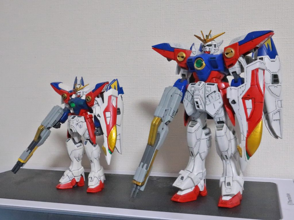 2014年発売キットであるHGAC1/144ウイングガンダムゼロと比較。こうして並べると本キットはプロポーション自体はTV版の設定に忠実でマッシブなものの、今の目で見るとライフルのグリップ位置やシールドのジョイント部の関係で武装が垂れ気味に見えてしまいますね。このキットではアニメ本編やゲームで見られる「シールドを装着している左手にライフルを持たせ右手にビームサーベルを装備させる」という姿を再現するのがすごく大変でしたがHGACはライフルを左腕に持たせることがすんなり出来てすごく感動した思い出があります。これが19年の進化…!