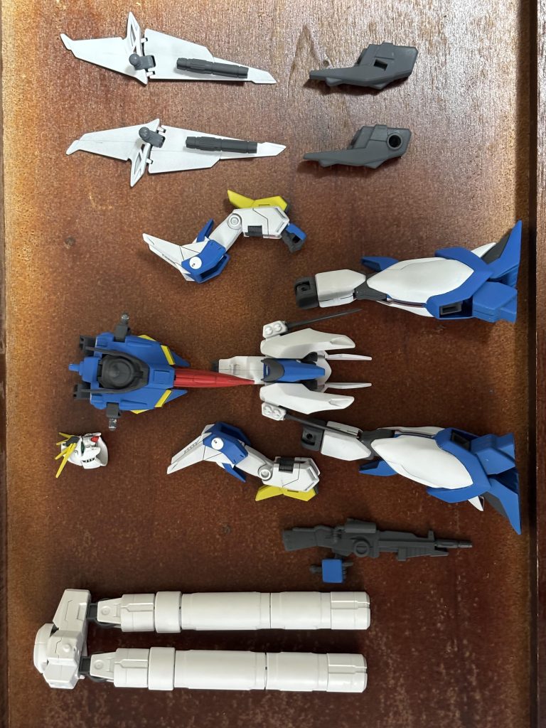 色分けして塗装したパーツです。ここから一気に完成まで飛びます(作業途中の写真は撮っていませんでした) ディテール追加はふくらはぎ部分と肩にスジ彫りを追加した程度で、残りは既存モールドの彫り直し程度です。本当はもっと入れたかったのですが、曲面の多いデザインゆえに断念しました。 また、同様に曲面の加工のためケガキ針やチゼルが上手く使えなかったりと、単純なモールド追加ですらかなり苦戦し、ミスも多くなってしまったのですが(そのためよく見ると線がガタガタだったりします)、はみ出した部分は溶きパテを使ってリカバーしました。今回初めて使ったのですが、かなり使い勝手が良かったです。 ただ溶きパテは胸のエンブレム消しにも使ったのですが、大きな穴埋めとなるとやや手間がかかりそうだったので、簡単隠しをしてしまえの気持ちでプラ板を長方形にカットして貼って隠してます。 下部にあるのは30MMのオプションパーツである大型プロペラントタンクです。バウにも背部プロペラントタンクが標準で付いているのですが、小さくてあまりインパクトがないため差し替えにしました。大型プロペラントタンクの接続ジョイントは3mm穴、バウ背部のジョイントはそれより大きなもの、つまりそのままでは入らないため、簡単な加工(軸をヤスリでただ削って細くする)を行ってます。