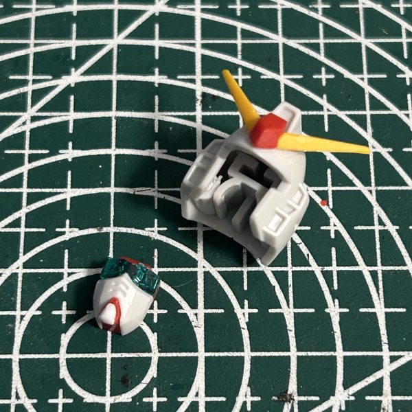 頭部の合わせ目消しのために後ハメ加工を施しつつ、顔の部分が子供っぽい感じがしたので幾つか改修しました。マスクの下部を削りシャープに顎先をプラ板で延長アンテナのシャープ化 （1枚目）