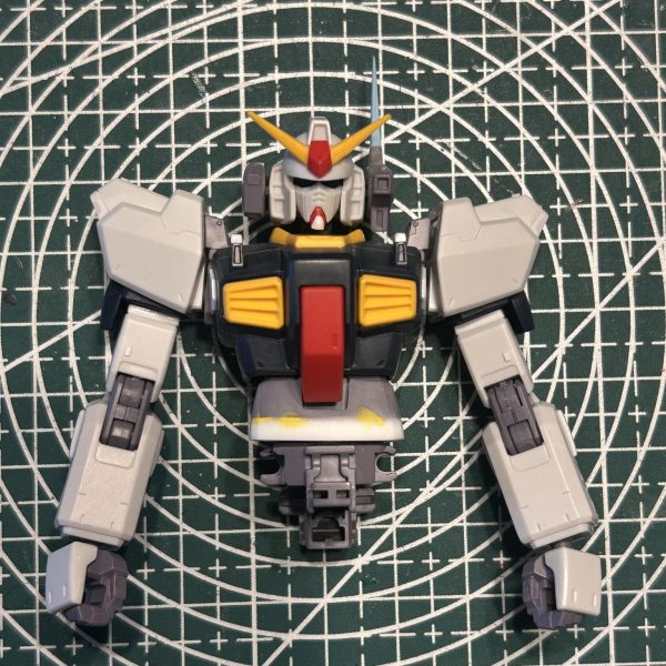 首と胴体を延長したのに合わせて腕も少し延長しました。肩アーマーはあっさりし過ぎに感じたのでスジ彫り追加とプラバンチップの貼り付けを施しました。また、使用しない右腕のポリキャップ穴はプラ板で作ったディテールで塞いておきました。バルカンポッドに関してはアンテナをもっとシャープにしたかったので、オリジナルは切り落としとがったものに差し替えました。（2枚目）