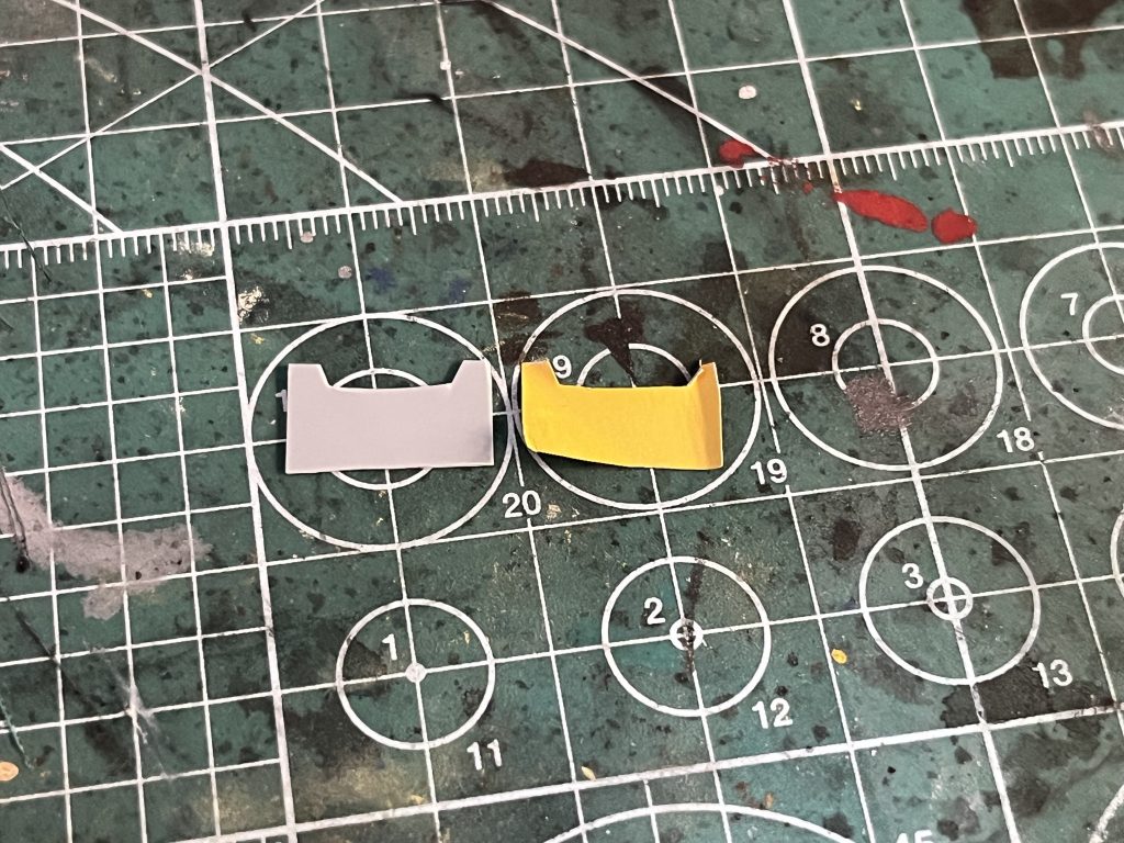 作業場が汚くて申し訳ないんですが、シールを0.3mmのプラ板に貼って、その形に合わせてハサミとニッパーで切り出しました。これを各シールパーツごとに作って、黄色で塗装して上から貼り付けてます。本来より少し厚みが出てしまいましたが、チープな感じは消すことができたのでやって大正解でした！