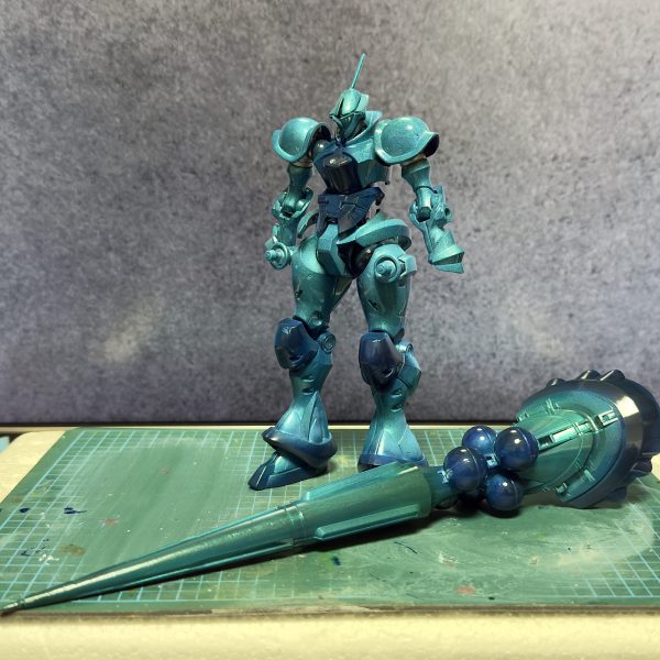 ① 制作途中でしたが、甲冑みたいで良い色だったので仮組してみました　白色のパーツはプレミアムミラークローム　灰色のパーツはガイアのサフシルバー　黒色のパーツは無塗装　　乾いたと思って触ったら少しハゲてしまいましたが、まぁこの後も塗り重ねるので気にしません　　周りの色や灯りの色で変わって見えるのが面白いですね　もう一機買って、この色合いでもっと綺麗に仕上げるのも良いかも　　　② 全身を青っぽくしたらランバラル専用機みたいになりました　でも目指してるのはランバラルじゃないので、まだまだ途中です　　③ 青や緑を重ねてクリア吹きました　肉眼だともうちょっとエメラルドグリーンっぽいんですけど、iPhoneのカメラだとグフカスっぽく見えますね…　目標まではもう何段階か手を加えないといけませんが、だいぶ良い感じになってきました　　（7枚目）