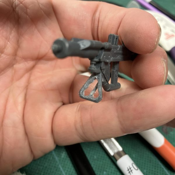 (zaku-kao2)軍警ザクですね、ザクマシンガンの前側、三角形の部分はデカール貼りかな？🥳とか考えてましたが、コレ、パッケージ見ると棒状の三角デザインが省略された結果の三角形ですね😑というわけで、ピンバイスやらダイヤヤスリで貫通させてみました😉しかしながら、真鍮線でここだけスクラッチの方が早くて簡単かもしれませんね😵‍💫　ちょっと白化してますし（ニッパーで強引に短縮しようとしたツケ😮‍💨）「普通」に戻す作業は完成後はあまり気付きませんが、本人だけはココ見てニヤニヤ出来るという🤤🤤で、どうやらリックドム(GQ)のジャイアントバズもこのタイプらしいのでおかわり確定😎（5枚目）