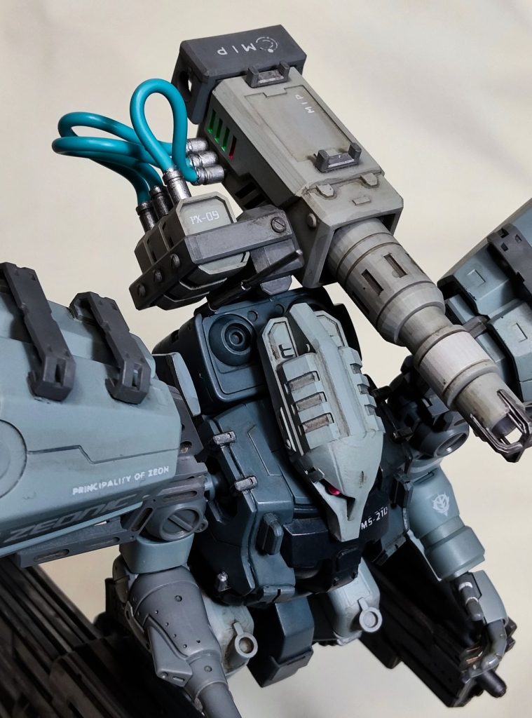 機体解説・本機は「盾なんかいらない」を体現する徹底した後方支援機。遠距離からの援護射撃に特化している。・よって近接武器なし、バックパック縮小も「速度より航続時間を優先」するための処置。・メインコックピットは胸部に維持。・副操縦士は頭部のサブコックピットで索敵/監視/射撃補佐/状況管理/通信/パイロットの精神的サポートを行う。・ただし頭部はほぼ無装甲で、被弾時の即死は免れない。 武装解説MIP社製 PX-09 パルス・キャノン(中距離用)(Pulse eXperimental-09)・一点突破よりも弾幕形成を重視。・極短周期の断続ビームを連射可能。・リコイルによって最大12発を連続射出でき、再充填には約2秒。・継続的な火力投射によって味方の突撃を支援する役割を担う。・通常のビーム・ライフルと違い、収束度は低めだが、広範囲に薄く弾を撒けるのが強み。Z2TEX社製 VEM-04A「VENOM」 電磁アサルトライフル・正式名称は Violent, Energy, Neutralizer Overdrive Module「暴力的なエネルギーで敵機能を無力化する、限界出力モジュール」。・一部の資料では Violent-Electro-Magnetic とも表記される。・口径は小さいが初速10km/sという桁外れの兵器。・直撃すれば即死級の破壊力を持つ、トンデモ系実験兵装。・中距離のパルス・キャノンと組み合わせ、長射程を補完している。ジオニック社製 3連装ミサイルポッド(MPL-3N-Mk.2)・支援機としての「遠距離火力」の一端を担う。・大型兵装と合わせ、安定した支援力を確保。Z2TEX(ジーツーテックス)・正式には Zeonic-ZIMMAD Technical Experimentation eXtension。・ジオニック社とツィマッド社が共同で設立した技術実験拡張部門。・主に試作機や実験兵装の開発・運用を担っており、革新的な新技術兵装を多く生み出してきた。・ヴェルナーも設立初期に短期間ながら深く関わっていたと言われている