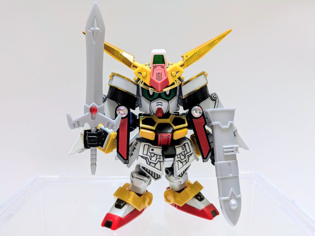 私説・ＳＤ戦国伝／弐十國戦記〜光と闇の大戦〜【第３話／三兄弟】地上全土に異変が起こり、白帝らが出立する数日前。天宮の隣国であり、天宮大将軍の弟が統治する真駆国。長刀や薙刀など長き得物の国と呼ばれるほど武術が盛んな土地。白帝の従兄弟であり皇子である衛宇吾は父から国宝である〝光の神器〟銀狼剣が何者かに盗み出された事を知らされる。厳重な警備を音もなく掻い潜った奪取劇に衛宇吾はある疑念を抱く。不安を胸に秘めたまま国の精鋭を集めた捜索隊を率い、追跡の旅へ出る。たが、その裏で弟の逞鍛（ティターン）にだけは父にも明かさぬ密命を頼んでいた。「真駆参を捜せ。彼が下手人でないことを祈る」真駆参は衛宇吾と逞鍛の実弟。清廉潔白の兄二人に比べて真駆参は幼い頃から危険な思想を持っていた。槍術の才覚がありながら武術の道そっちのけで真駆参は魔界に対する研究を隠れて続けていた。いつか魔界へ行ってみたい。それが真駆参が兄たちにのみ明かした夢であり、危険な野心だった。父はそれを知らない。だから銀狼剣を持ち出したのが真駆参かもしれないなどとは夢にも思わないだろう。衛宇吾自身、思い違いであってほしいと祈っている。「銀狼剣なら魔界の門を破壊できるとでも思ったのかよ。とうとう気が狂ったか、あいつ」「逞鍛、これは気の迷いで済む問題ではない。誰にも知られてはならぬ。我ら兄弟だけで事を収めねばならぬ。我が一族の尊厳のために」間違った判断であることは衛宇吾にも解っていた。父に告げ、真偽を確かめ、然るべき裁きを科さねばならぬ大事件なのだ。だが、弟の思想を知りながら自由にさせてきた兄の責任でもある。それにいくら皇子といえども軽い罰では済むまい。とにかく今は真駆参を見つけ出すことが最優先なのだ。その頃、兄の願いも虚しく銀狼剣を持ち出した真駆参は魔界の門へと辿り着こうとしていた。決して悪事を働きたいわけではない。父や兄たちが疎ましいわけでもない。ただ、幼い頃から抱いた魔界に対する魅力は日を追うごとに深まっていった。誰もが抱く何かへの憧れ。自分の場合、その対象が魔界だっただけ。片道切符でも構わない。夢を叶えて絶えるなら本望だ。あとのことは才ある兄たちが巧くやってくれるだろう。魔界の門が眼前に聳え立っている。絵でしか見たことがなかったが本当に巨大だ。大海原へ切り出した崖の先端に城のごとく鎮座している巨大な鉄扉。まさに人知を超えた神の創生物。門に続く登り坂のあちこちに札の貼られた縄が巡らされているが警備や門番のような者の姿はなかった。番を立てる意味もないほど結界が強力ということか。おや…誰かいる。真駆参は思わず足を止めた。門の麓に先客の姿があったのだ。武者鎧を脱いで傍らに置いているからどこかの武者か。座り込んで何かをしている。真駆参は再び足を進めた。これが最悪の出会いとなることを知らずに…。次回を待て！