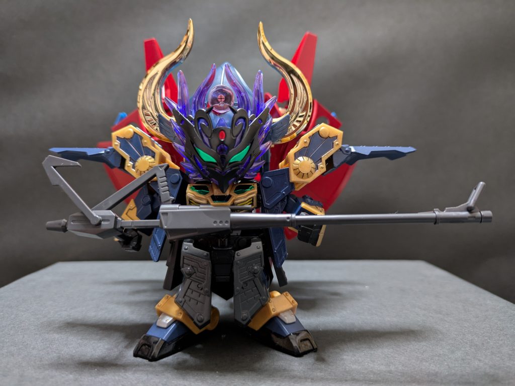 私説・ＳＤ戦国伝／弐十國戦記〜光と闇の大戦〜【第４話／侵攻】激しい雷鳴が轟き、大地が揺れ、空は漆黒の雲に覆われ、低いうねりをあげている。逞鍛は眼前に聳え立つ魔界の門に向かって駆けた。いったい何が起こったのだ。いくら〝光の神器〟といえどもたった一振りでは結界を破る事など到底不可能のはず。醜い争いに繋がる強大な力を忌み嫌った光の神がそれを分割して生み出したのが〝光の神器〟であるのだ。それは世に二十存在すると云われている。二十分の一の力では小さな傷をつける事も叶わぬと父が言っていた。揺れ動く大地に足を取られながらようやく門に辿り着いた逞鍛は割れんばかりの弟の叫びを聞いた。「兄者！　兄者！」逞鍛は目を疑った。魔界の門に小さな亀裂が入り、真駆参がそこに吸い込まれていたのだ。下半身は既に没し、右手に握った剣を突き立ててどうにか持ち堪えていた。その剣、銀狼剣は紛れもなく真駆國に受け継がれし〝光の神器〟だった。「真駆参！　この大馬鹿野郎が！」「すまぬ。兄者、すまぬ。こんな事になろうとは…俺はただ…俺の夢を…」逞鍛が全速力で駆け寄り、手を伸ばしたその瞬間だった。亀裂の中から巨大な影が飛び出し、逞鍛を跳ね除けた。態勢を立て直し、刀を抜いた逞鍛の前に現れたのは不気味な四つの眼を持つ怪鳥だった。「馬鹿な…結界が護るこちら側に来られるはずは…」「選ばれし者たちはいただいてゆく…まもなく地上は闇に包まれる。芽はすでに放たれている…」怪鳥が真駆参の身体を覆い込み、亀裂の中へと引きずり込んでいく。「待て！　弟を返せ！」「兄者！　地上はすでに細胞に…」逞鍛は金縛りにあったかのように動けず、魔界へと吸い込まれていく弟の姿を見つめることしかできなかった。真駆参を飲み込んだ亀裂はゆっくりと閉じ、地の揺れは収まった。静寂が戻るとともに逞鍛の身体に自由が戻った。救えなかった…すべて夢であってくれと己の無力さを呪ったが、突き立った銀狼剣がこれは紛れもない現実だと物語っている。一刻も早く兄上に知らさなければ。真駆参…弟が握り締めた剣を回収し、逞鍛は踵を返した。その瞬間だった。背後に巨大な何者かの気配を感じ取った。ずっしりと重く、冷たい悪寒が込み上げる。反撃の暇もなく、首筋に鋭い衝撃が走り、逞鍛の意識は深い暗闇へと堕ちていった。次回を待て！！