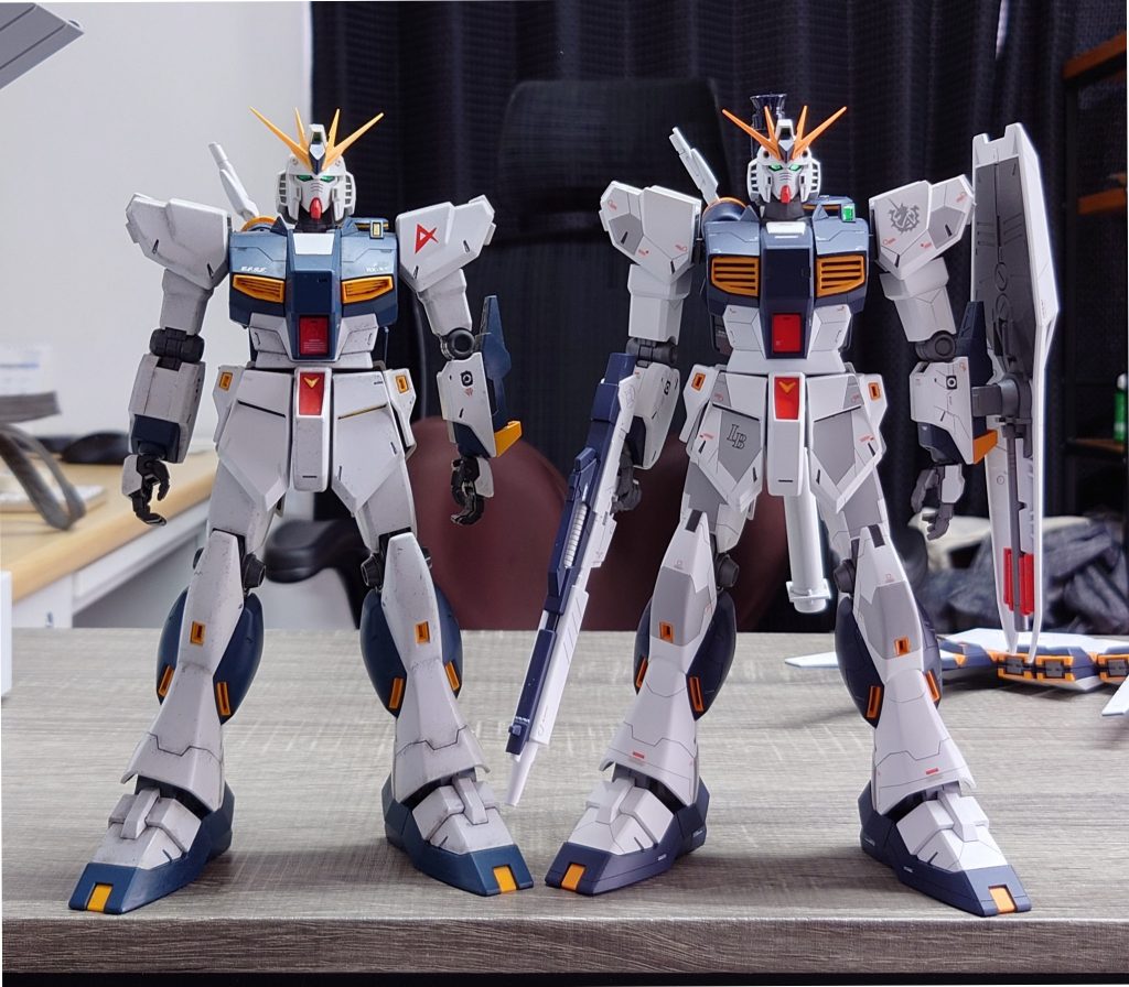 左右どちらも24年前のガンプラ。ほぼ素組の旧キットもこれはこれでカッコいい。陸ガン、RX78のV1.5、アレックス、フルバーニアンあたりはみんな顔が大きめ。そして大渕デザインのアレックスとνはウエストがやたらと短い。この年代のキットは総じて頭が大きい。そこへ小顔アシナガのverKa頭を乗せただけだと1/144の頭が1/100に乗っかってるような見た目になる。そこで胸部を小さくするために幅詰めとなるが、旧キットもフレーム構造で肩関節が入ってる。そしてこの関節が弱い。ちょっと振動与えただけで下がるくらいヘタれるのが早い。踏ん張りのきかないダメ関節なので引き出し式ジョイントに変えている。組んだ人ならわかると思うが、写真の旧キットはいかり肩マックス状態でこの位置。改修後はこの高さが通常。ウエスト延長前は胸腹腰のユニットごとに真横にブツ切りしたのを重ねたアルベガスのような見た目で体のラインが不自然になっている。正面からみるとそうでもないが、斜めからみたりポージングさせてみると体のラインが破城しているのがわかる。横に広く垂れ下がっている胸とガッチリした腰アーマーに寸足らずなウエストが窮屈そうに挟まれているような見た目。ダイエットに失敗した相撲取りみたいである。そこでウエスト延長になるわけだが、伸ばしただけでは胸と腰のラインが破綻するので、男らしい逆三角形を崩さないバランスを心がけた。とうぜん横からの見た目も大切なのでコクピットハッチだけでなくダクトも胸筋のようにビルドアップしている。脚はヒザアーマー以外は旧キットのままだけどかなり長いことがわかってもらえると思う。長い足と延長した胴体とくれば、相対的に腕が短くなる。そこで肩を上方向へ大きく、上腕は1mm厚のプラ板で一周ぐるっと巻いて太く長さも3mm延長している。最近のverkaとかRGは足が長すぎるんだ。それをわかるんだよ。