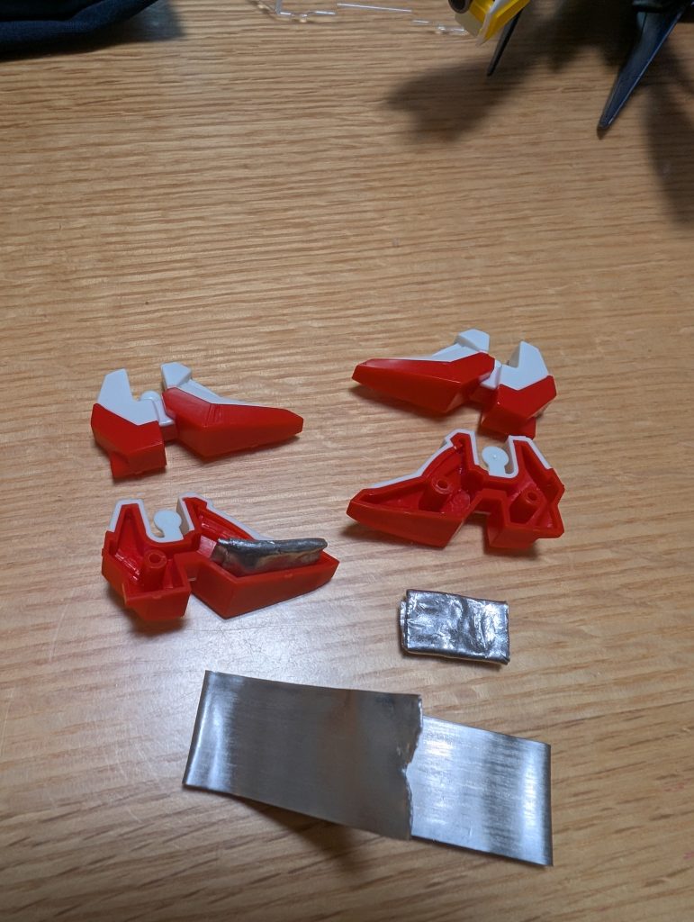 重りの仕込み素立ちのときに重心が後方にかかり倒れやすいので、重りを仕込むこととした。釣具のガン玉を仕込む作例をいくつか見た。それならと、同じ釣具の「板おもり」で代用。簡単に手でちぎれるので加工はしやすい。ちぎって折ってパーツの隙間に仕込むだけ。パーツ同士で合わせるとガッチリホールドなので接着不要。片側につき4g。超合金ばりの重さをGetし、立位は安定感が抜群に増した。でも足を設置させないポーズとかはデリケートなゼータの股関節とか負荷がかかるかな？&nbsp;