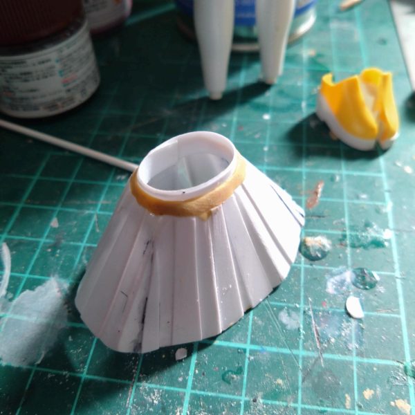 チナッガイ改造の続きです。後頭部はこんな感じになりました。スカート部分は昨日制作。腰のパーツに帯のように巻き付けたプラ板に、台形のようにカットしたプラ板を貼り合わせて制作。瞬間接着剤塗っては瞬着スプレー…でこんな感じに出来ました。 今日は昨日制作したスカートより少し短くしたプラ板をスカート一周以上の長方形型に切り取りライターで炙っては少し曲げ、そしてハサミで上から下に向かって細い3角状に切れ目を入れてその分を無理矢理曲げて瞬間接着剤とスプレーで硬化。その繰り返しで一周回ってできたのがメイド服のフワフワしたスカート状の白い部分っぽいものを制作。まだガタガタですが接着部分の隙間等に瞬間接着剤を裏表両方塗ってスプレーで硬化。その後サーフェイサーホワイトをベタベタと筆塗りしました。現在ここまでですが乾燥後にまた瞬間接着剤塗る予定です。この後ヤスリがけしたりで角を落としていく予定です。多分プラ板髪型制作のようにサフと瞬間接着剤が角を滑らかにしてくれるはず。後は靴なんですが幅広でカッコ悪いので左右半分にカットして真ん中削って接着して幅詰めしました。くるぶしあたりの丸いモールドも削りました。スカートが上手くいけばまた来週末にはかなり進めれると思います。🤔（2枚目）