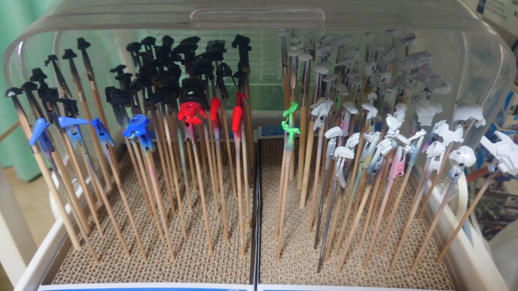 お次は基本塗装。サフ→基本色(→クリアや蛍光)の順で塗りますサフ・ソリッド・メタリックは塗料の噴霧量を少ない状態で吹くいわゆる砂吹きを2周したあとに表面が濡れるくらいに吹いてフィニッシュ。ただし吹きすぎて隅に塗料が溜まらないようにします。これはもう練習あるのみでしたクリア・蛍光は砂吹きで本当にうっすら色づくくらいで5分程度の1度目乾燥、もう一度砂吹きしてやや色づくくらいで2度目の5分乾燥、3回目で濡れるくらいキッチリ色を付けていますエアブラシを使う上で最大の壁と思うのは「希釈率」だと思っています。慣れている人や玄人は「塗料ごとに調整している」とか「牛乳くらいの濃さ」と言ってます。ド素人には全く理解不能な世界ですそんな中とあるYoutuberの方がある種の極論を言っていたのでそれにあやかりました。結果、「ラッカー系は種類に関係なく『１：２』」で希釈しています。正確にはそこからさらに自己流で「１：２で希釈してさらに薄め液1ml追加」で希釈しています。現状はこれで薄すぎ・濃すぎということはなく、問題なく塗装できていますちなみに水性塗料は公式(クレオス)が「１：１」を推奨しているので「１：１で希釈後さらに薄め液1mlで希釈」にしています