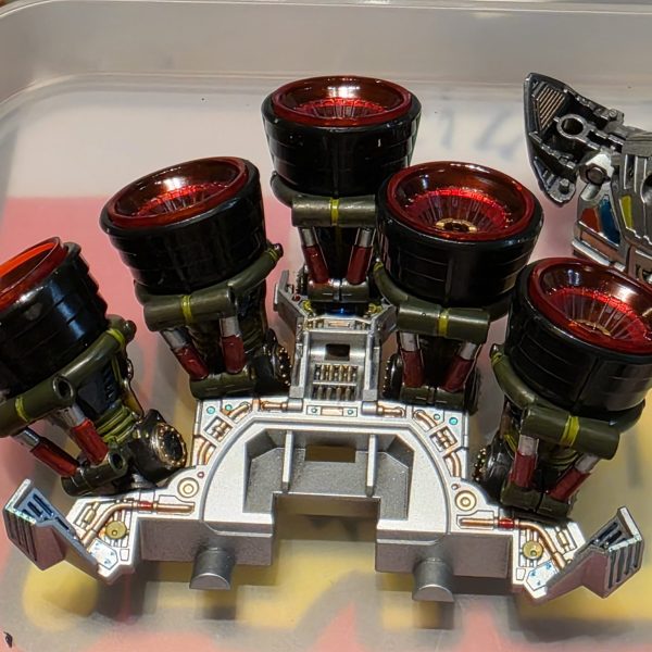スラスタ－は6基分あるけど使うのは5基。スラスタ－の裏側とか取り付け部分なんて絶対に見えなくなるけど塗り分けてみた。リアスカート上面のパネル「I1 16」の部品はなぜかクリアグリーンになってる。スラスタ－カバーと同色だから、通常色ならグレーかシルバーの成型色だったはず。仕方ないのでここも塗り分けることに。（1枚目）