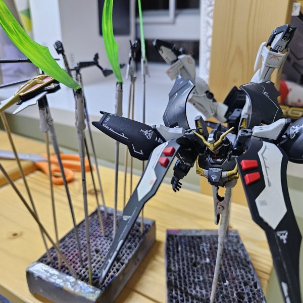 金曜日にうｐする予定のデスサイズヘルなんだけど昨日から会社に飾っています今撮った写真を確認中なんですけどどうも制作過程の話を入れると写真枠が足りないようでこの話は制作ストーリーで投稿しましょう3年前に作ったデスサイズはキットの成型色を無視してよりアニメに近い暗いグレーで塗装したんですが今回のデスサイズヘルは成型色を参考して本体は少しダークブルーよりな色でそしてアクティブクロークの部分はブラックに近いジャーマングレーで塗装しました理由と言えば、追加の新装備に特別感を持たせたいからですね完成した後はほぼ違いが見えない、というのは仕方ないですけれど（3枚目）