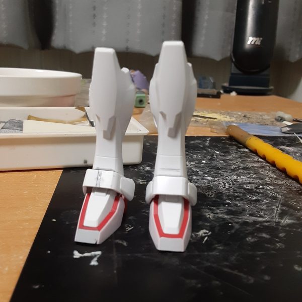 バルバトスの肉抜きを埋めようとしたらエポキシパテが余ったので、0ガンダムの脚やシールドに使う事に。で、そのままの流れで0ガンダムの製作に突入。 良くない兆候だけど、バルバトスの方はシリンダーをあと一本作ればいいだけだからすぐ終わるはず。いいんだいいんだ、これは浮気じゃないんだ！ この0ガンダム、キットではスマートな体型で、特に脚部は腿が短く脛がかなり長いガンダムフレーム(うわああぁ!)のようなバランスになっています。一方劇中では頭身がそこまで高くなく、ムキムキな太腿をしていて、キットとは全然違う体形。なので自分にできる範囲で「細さ」を打ち消すような改造をしてみます。 まず足首を裏打ち後に正面で1.5mm短縮。左右から0.3mmプラ板でサンド。少しでも太く見せるため、C面を無くしています。 関節ブロックを上下に3mm短縮、アンクルアーマーを中央で1mm幅増し。そのままではアーマーを付けられないので脛下端のPCにかぶせるような形のブロックをプラ板から自作し、アーマー裏とBJで接続。強度が足りないのでこの段落に書かれている部分だけで0.3～0.5mmの真鍮線を７本も使っています。 脛は側面中央のエッジを起点に、正面のみを斜めに2.5mm短縮。BJとの干渉で脛を前に倒す方向へはほとんど動かなくなりましたが、横への可動範囲はほぼ変化なし。 これらの工作で脛や足首がいくらか太く、短く見えるようになったはずです。高さが2mm弱低くなったので、その分は腿を伸ばしてバランスをとる予定。（1枚目）