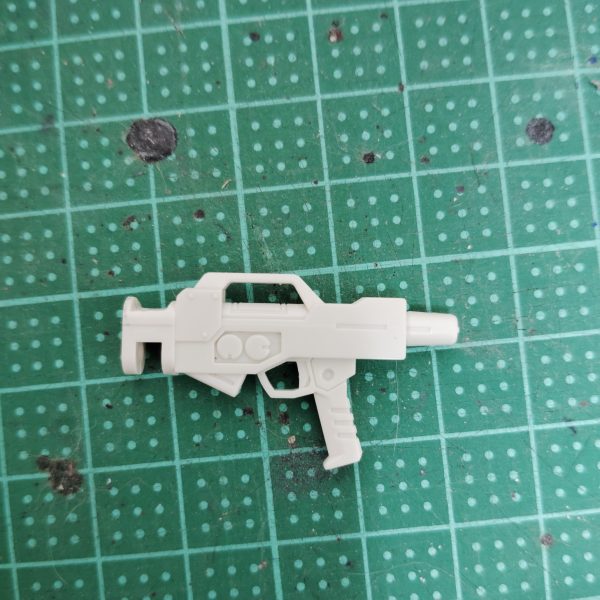 　ビームライフルのストーリー投稿第９弾です。　今回は、前回予告した追加パーツをビームライフルに取り付けるための下準備を行います。　もともと陸戦型ビームライフルの銃身下部にあったエネルギーパックと思しきパーツを、ヤスリとデザインナイフで切除していきます。　空いてしまった隙間は、パテなどで埋めるよりも手っ取り早いのでは、と考え、0,3mmのプラ板で塞いでしまいました。　前回のスコープと同様、最終的にはパテなども使ってわずかな段差なども完全に埋めてしまいたいのですが、それはある程度加工がすんでからになりそうです。　これで下準備が整ったので、次回からようやく追加パーツを製作していきたいと思いますが、本日プラ板を切り出した段階で、作業量とその手間がなかなか大変そうだと予想できてしまいました・・・。　完成まではまだまだ掛かりそうなうえ、次回完成品として投稿するモノはこのビームライフルとは全く関係ない機体なのですが、どうか気長に、ネタバレなしでお付き合いください。（2枚目）