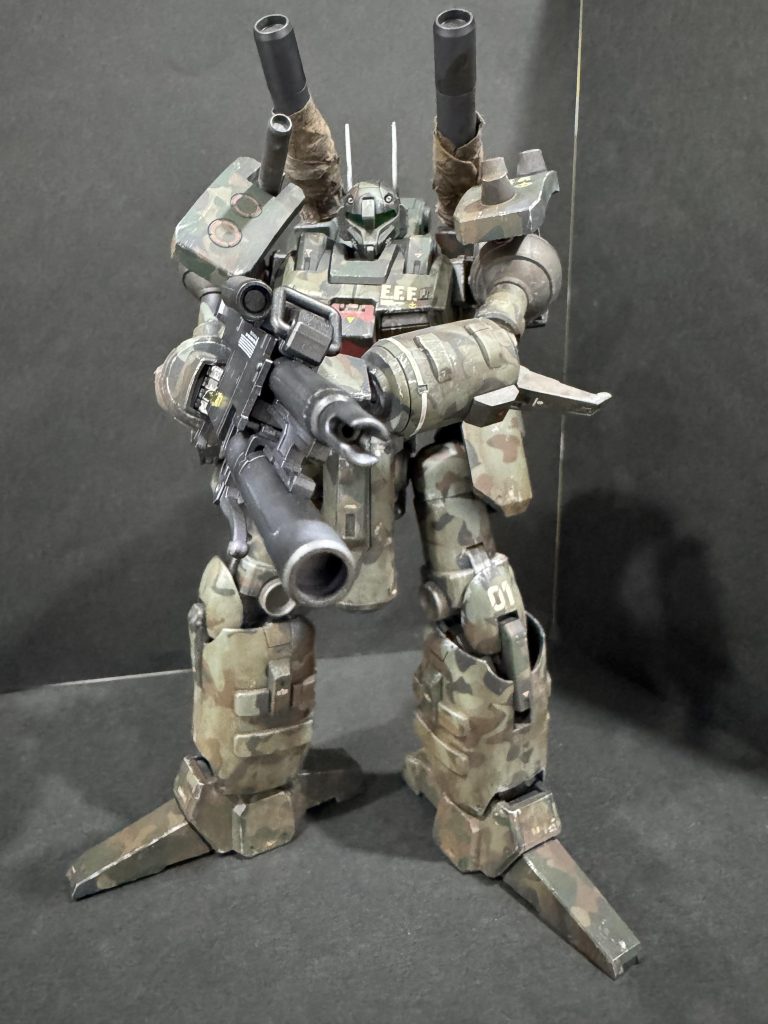 迷彩=陸戦機体なので汚しをすることは作成前から決めていましたが、完全思い付きでキャノン砲身のサーマルスリーブを取り入れてみました。汚しは以前と同様、TAMIYAの墨入れ塗料 ダークブラウンやブラウンを機体全面に塗りたくり、綿棒やキムワイプで拭いたりしています。ダークブラウンやブラウンで汚れたキムワイプがサーマルスリーブのように見えてきたので、塗料を少し吸わせて砲身にぐるぐる巻きにしてみました。ビームキャノンにサーマルスリーブが必要かどうかは定かではありませんが、思い付きにしてはよく出来た方かなと思います。