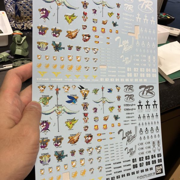 さて、ハイザックカスタム、大好物のデカールタイム、トップコート前の一手間ですね🥳というわけでディターンズはティターンズでもA.O.Zらしくテストチームの試作機としてTTTマークを使用しましょう🥰、、う〜ん、流石に初期のA.O.Zデカールは経年劣化が著しい😑特に白系はセピア化してる、、😅大判のプレバンデカールからマーキングを拝借しベースはコーションデカールですね、オレンジ&ホワイトのツートンが良さそう😉TTTとなると、指先はやっぱり赤ですね☝️🖌️使い捨て筆でホワイト下時に赤塗装、ハミ出した部分は新兵器のスミ入れ筆ペンでリタッチですね〜😬　ゴマカしやすい🥳（3枚目）