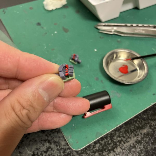 さて、ハイザックカスタム、大好物のデカールタイム、トップコート前の一手間ですね🥳というわけでディターンズはティターンズでもA.O.Zらしくテストチームの試作機としてTTTマークを使用しましょう🥰、、う〜ん、流石に初期のA.O.Zデカールは経年劣化が著しい😑特に白系はセピア化してる、、😅大判のプレバンデカールからマーキングを拝借しベースはコーションデカールですね、オレンジ&ホワイトのツートンが良さそう😉TTTとなると、指先はやっぱり赤ですね☝️🖌️使い捨て筆でホワイト下時に赤塗装、ハミ出した部分は新兵器のスミ入れ筆ペンでリタッチですね〜😬　ゴマカしやすい🥳（6枚目）