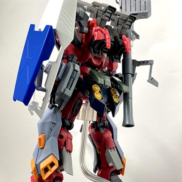 軽キャノンはGQガンダムより腕や脚が気持ち太くはなっていますが、ボディの大きさと比較するとボリューム不足に思えた為、デュエルブリッツのアーマー部分をミキシングしてマッシブになればいいなと作成開始しました。脚部は排気ダクトとスラスターを追加し、デュエルブリッツの追加装甲を装備バックパックはオリジン版ガンキャノンのビームキャノンに変更、ハイパーバズーカとシールドをマウント頭部は01ガンダムのようにV字アンテナをつけようとしましたが、キャノンと干渉するので、サイドに設置腰は広すぎるように思えたので、赤いガンダムの腰に変更し、フロント、サイド、リアと装甲追加胴体はタンクを中に埋め込み、肩にはミサイルコンテナのような蓋を追加肩はデュエルブリッツの肩アーマーを前後に取り付け、上部にはゼフィランサスの肩パーツをつけています。腕にはデュエルブリッツの装甲をつけていますが、ランサーダートやスレイプニールは流石に合わなかったので二連装ビームライフルっぽいものを右腕に、左腕にはジェスタのビームサーベルラックを装備ビームライフルは軽キャノンのビームライフルにデュエルブリッツのビームライフルパーツを切って貼って長さをアップまだテープで仮止めの箇所ばかりですが、軽キャノンとデュエルブリッツ装甲は新しいキットなのでサイズ的にはフィットしている気はしますね。（6枚目）