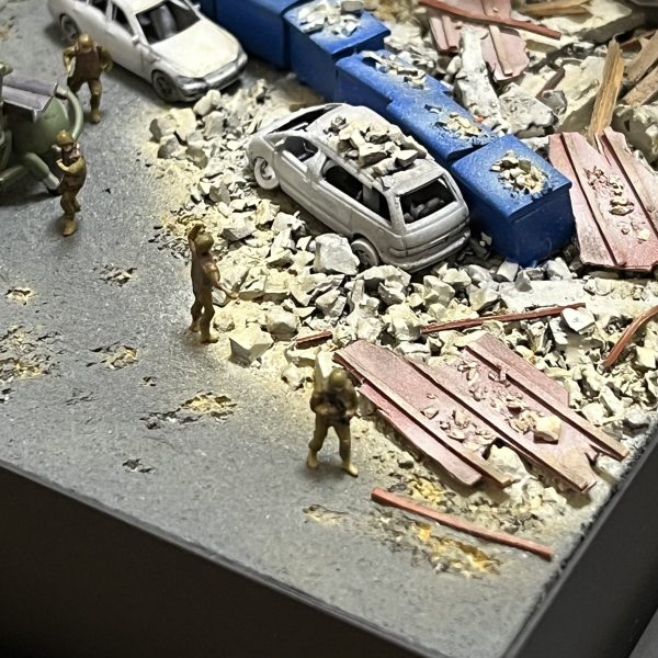 負傷兵フィギュアを追加しました。UMRCのオニー・カスガはいませんが😅よろしければ画面をタップし拡大してご覧に下さい。劇中では死傷者の描写が多くて戦争映画を観ている感じでした。あの悲壮感をガンプラで戦場ジオラマとしてしかも1/144のミニスケールで表現できてたら申し分ないと思ってます。マゼラアタックもウェザリングに手を加えました。雨垂れに埃が付着した感じで全体的に汚してます。アスファルトも少し気に入らなかったので表面をけがいてダメージを加えています。あと心残りとなっているのが建物のウクライナ語の看板です。ロケハン建物写真の正面エントランス上とオーニングテント上に取り付けられている物です（テント上のアルファベットは全く読み取れません😅）。何度となく挑戦してますがアルファベットをうまく切り抜けず挫折を繰り返してます。ミリタリースケールのジオラマだと建物の看板とか結構リアリティ出せる要素だったりするんですけど、デザインカッターで切り抜くにも1/44のサイズは小さ過ぎます😭まだ時間ありますから引き続き頑張ろうと思います。（5枚目）