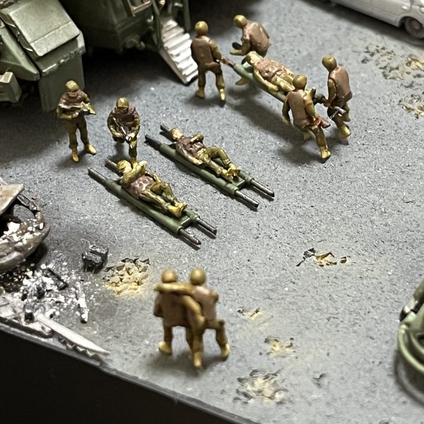 負傷兵フィギュアを追加しました。UMRCのオニー・カスガはいませんが😅よろしければ画面をタップし拡大してご覧に下さい。劇中では死傷者の描写が多くて戦争映画を観ている感じでした。あの悲壮感をガンプラで戦場ジオラマとしてしかも1/144のミニスケールで表現できてたら申し分ないと思ってます。マゼラアタックもウェザリングに手を加えました。雨垂れに埃が付着した感じで全体的に汚してます。アスファルトも少し気に入らなかったので表面をけがいてダメージを加えています。あと心残りとなっているのが建物のウクライナ語の看板です。ロケハン建物写真の正面エントランス上とオーニングテント上に取り付けられている物です（テント上のアルファベットは全く読み取れません😅）。何度となく挑戦してますがアルファベットをうまく切り抜けず挫折を繰り返してます。ミリタリースケールのジオラマだと建物の看板とか結構リアリティ出せる要素だったりするんですけど、デザインカッターで切り抜くにも1/44のサイズは小さ過ぎます😭まだ時間ありますから引き続き頑張ろうと思います。（4枚目）