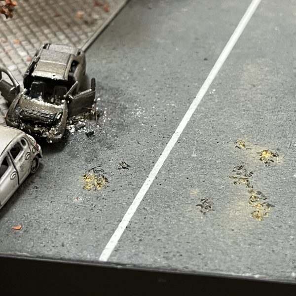 負傷兵フィギュアを追加しました。UMRCのオニー・カスガはいませんが😅よろしければ画面をタップし拡大してご覧に下さい。劇中では死傷者の描写が多くて戦争映画を観ている感じでした。あの悲壮感をガンプラで戦場ジオラマとしてしかも1/144のミニスケールで表現できてたら申し分ないと思ってます。マゼラアタックもウェザリングに手を加えました。雨垂れに埃が付着した感じで全体的に汚してます。アスファルトも少し気に入らなかったので表面をけがいてダメージを加えています。あと心残りとなっているのが建物のウクライナ語の看板です。ロケハン建物写真の正面エントランス上とオーニングテント上に取り付けられている物です（テント上のアルファベットは全く読み取れません😅）。何度となく挑戦してますがアルファベットをうまく切り抜けず挫折を繰り返してます。ミリタリースケールのジオラマだと建物の看板とか結構リアリティ出せる要素だったりするんですけど、デザインカッターで切り抜くにも1/44のサイズは小さ過ぎます😭まだ時間ありますから引き続き頑張ろうと思います。（6枚目）