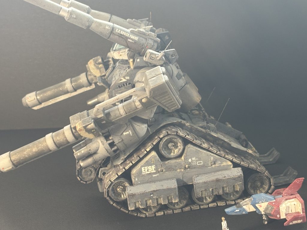 終戦間もない宇宙世紀0080年の夏。連邦政府は復興アピールのために、パリ〜アフリカ間をモビルスーツで走破する、かつての人気ラリーを復活させようと考えました。八州重工は、悪路走破性の高いガンタンクを改修してラリーへの参加を企画します。コアブロックを廃止して軽量化、エンジンと足回りを積み替え、上半身は前傾姿勢に変形し走破性を上げます。ホモロゲーションの要求する6カ月間に造られた12台に対し、軍はRX-75A1の形式名を与えました。