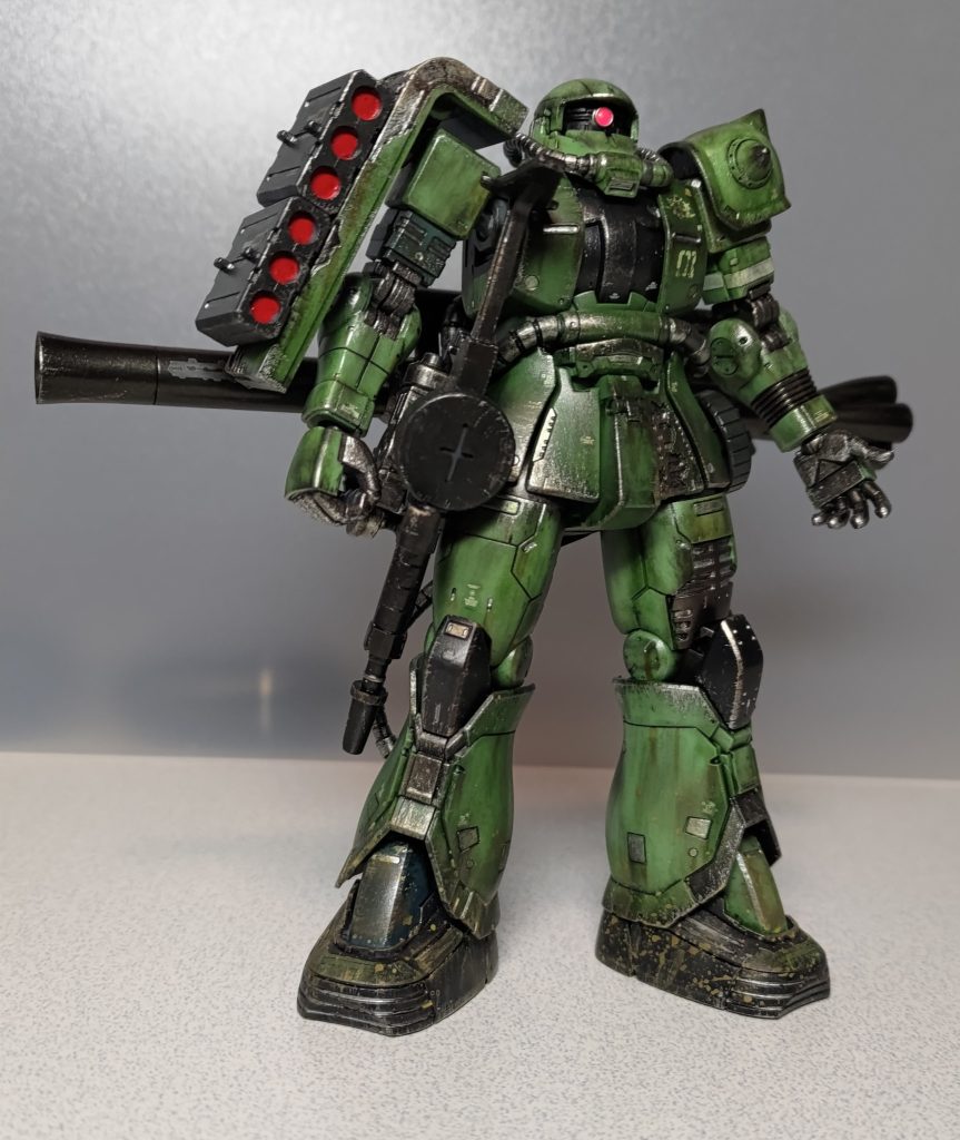 フロントショットです。武装追加に伴う改造箇所として、右腰にザクマシンガンを吊るすためのジョイントを追加し、ザクバズーカの予備弾薬とシールド内部にネオジム磁石を内蔵してます。<備忘録という名のカラーレシピ>黒：焼鉄色、黒鉄色、メタルブラック、ブラックグリーン銀：ガンクローム　　金：ゴールド赤：メタリックレッド　　桃：蛍光ピンク黄：蛍光イエロードライブラシ：タミヤアクリルのクロームシルバー泥はね：アクリルガッシュのイエローオーカー＋ホワイトウェザリングマスター：マッド、サンド、スス、サビ、ガンメタル緑は成形色です。本キットの特徴である破損部分を含めて機体各所の凹凸モールドにガンクロームを散らしてます。塗った当初は結構キラキラした感じだったんですが、これが馴染むくらい汚してやる！と思って頑張りました。どうでしょう