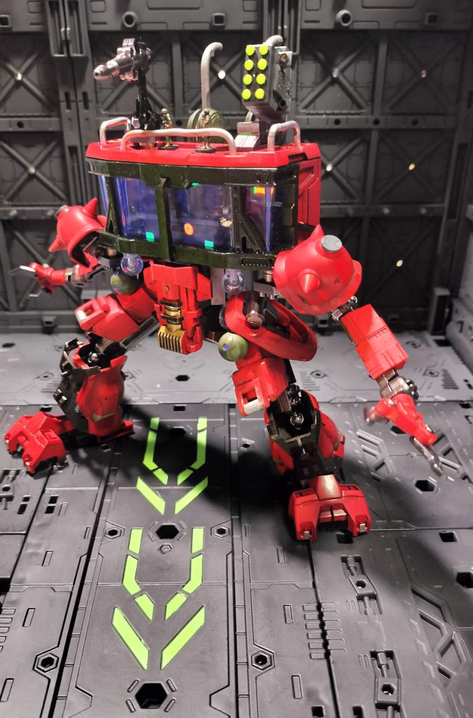 06)人手も装備も足りなくなったジオン残党軍が、司令室にも手足と武装を付けて戦線へ送り出すという妄想です。モチーフはWMですが削除されては困るので、足首にはガンダム（HGUCオリジン）の胸パーツ、脛はグフカスタムの余剰パーツなどを使い、司令室の操作パネルはモノアイ・ユニットも兼務させ、ガンプラミキシングであることをアピールしました。赤いペンキが残っていたので機体全体を赤で塗ったところ、基地のメンバーたちから「ユデガニ」と揶揄されたところから、機体名称が「YUDEGA-NNI」となったというのが、もっぱらのウワサ、ということにしました。