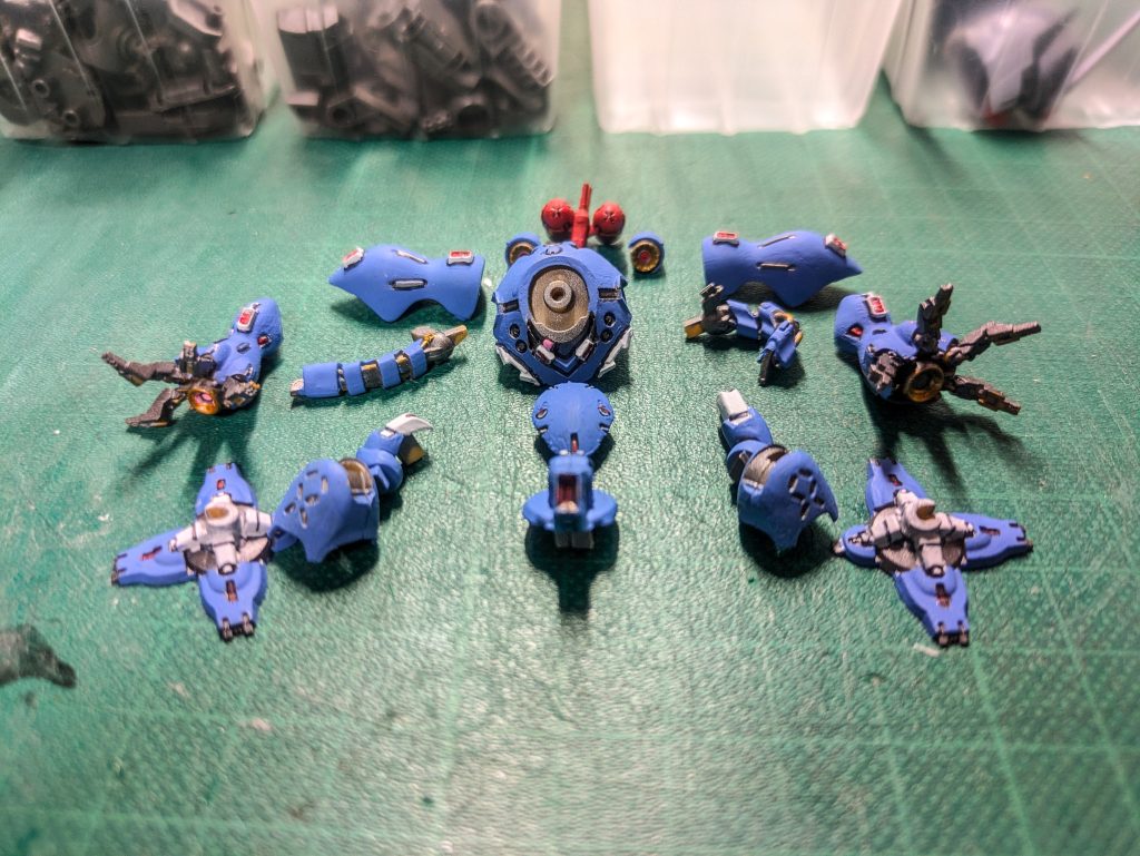 塗装済、組立・ウェザリング前の展開図。結構好きな構図です。カラーレシピ C：クレオス  G：ガイアカラー  シ：CITADEL   T：タミヤ全体：サフEVOホワイト（G）→サフEVOガンメタ（G）装甲：アッセンブルカラーブルー（C）＋アッセンブルカラーホワイト（C）白部：アッセンブルカラーホワイト（C）赤部：アッセンブルカラーレッド（C）金部：LIBERATOR GOLD（シ）バックパック：アッセンブルカラーレッド（C）＋アッセンブルカラーイエロー（C）モノアイ、ビームキャノン発射口：蛍光ピンク（G）スミ入れ：スミ入れカラーブラック（T）組み立て後全体：ウェザリングカラーグランドブラウン（C）