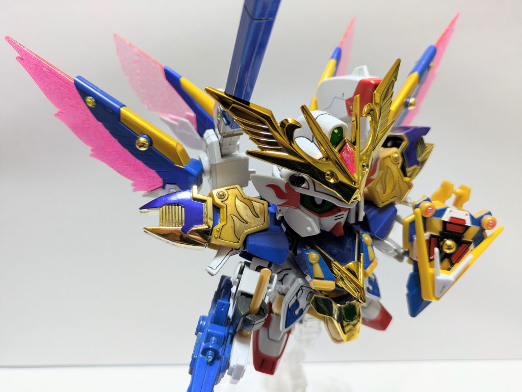 私説・ＳＤ戦国伝／弐十國戦記〜光と闇の大戦〜【第６話／奇襲】国土を二分した内紛が永らく続く武威ノ國。軍事力こそすべてを統べるものとして侵攻と台頭を続ける〝惨髑髏帝国〟に対し、もともと武力行使に消極的な大将軍率いる統治軍は疲弊しきっていた。弱体化した統治軍が手をこまねき戦火が広がっていくことに業を煮やした民衆は、民間抵抗組織〝神聖軍事同盟〟（通称・璃牙衆）を結成して対抗していく。武力での衝突に懐疑的な考えを持つ村の神社に身を寄せる若武者・舞威弐は、同盟への志願を求める周囲の声を程良く躱しながら遊び呆けていた。そんなある日、突如として起こった異変が魔界の門に起因するものではないかと推察した舞威弐は門目掛けて飛び出していく。武威ノ國は魔界の門に最寄りの国で、その警備や神事なども取り仕切っていた。雷鳴が轟き、地が揺れる。いったい何が起こっているのか…。とてつもない嫌な予感が全身に駆け巡る。昔からこういう時は決まって悪い事が起きる。そんな舞威弐の予想に反して周囲に静寂が戻った。空は依然として漆黒の雲に包まれているが、ところどころで光が漏れ始めていた。杞憂か？　いや…。その時、前方に駆ける一人の武者の姿が目に入った。肌も鎧も黒い、特徴的な武者だった。何が起こったのか知っているかもしれない。呼び止めるべく舞威弐も再び駆け出した。次の瞬間だった。黒い武者の背後、虚空を切り裂いて這い出すかのように巨大な影が突如として出現した。なんだ、あの化け物は…！？　馬鹿な…。気配など微塵も感じなかった。明らかに地上の者ではない。尋常ではない事態だ。結界は…？化け物は黒い武者の首筋に鋭利な尾先を突き立てた。黒い武者の悲鳴が響くとともに化け物の周りに黒い稲妻が走った。「やめろ！！」「強く、素晴らしい肉体だ。いただこう」「貴様、何者だ！！」「我が名は叛舞羅飛。魔界の海ヘビよ…」「結界の内に異界の者が存在できるはずがない。何をした！！」「貴様が知る必要はない。死ね」化け物の形が変わり、禍々しい仮面が黒い武者の顔を覆った。舞威弐が構えた次の瞬間、予想もしない方向から衝撃が走った。痛みに耐えながら舞威弐は思考を巡らせた。斬ればこの武者も死ぬ…。どうすべきか…。刀を握る手に躊躇いが伝わる。私怨は無い…だが、死ぬわけにもいかぬ。舞威弐は覚悟を決め、決死の技を放った。次回を待て！！