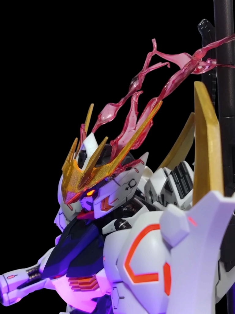 横顔です。アンテナブレードはルプスレクスっぽくするためジャンクパーツあさってたらみつけた多分1/144バルバトスの物だと思われるアンテナを切断して接着してみました。阿頼耶識リミッター解除の赤い光は透明プラ板を細切りして炙って曲げたりしてからクリアーレッドで塗装しました。取り付けはアンテナブレードと顔パーツの隙間に挟んでます。撮影中よく取れたりして苦労しました。ボディの色々な部分のモールド等には蛍光レッドで塗装してリミッター解除によりボディの各部からも発光するという設定にしてみました。 