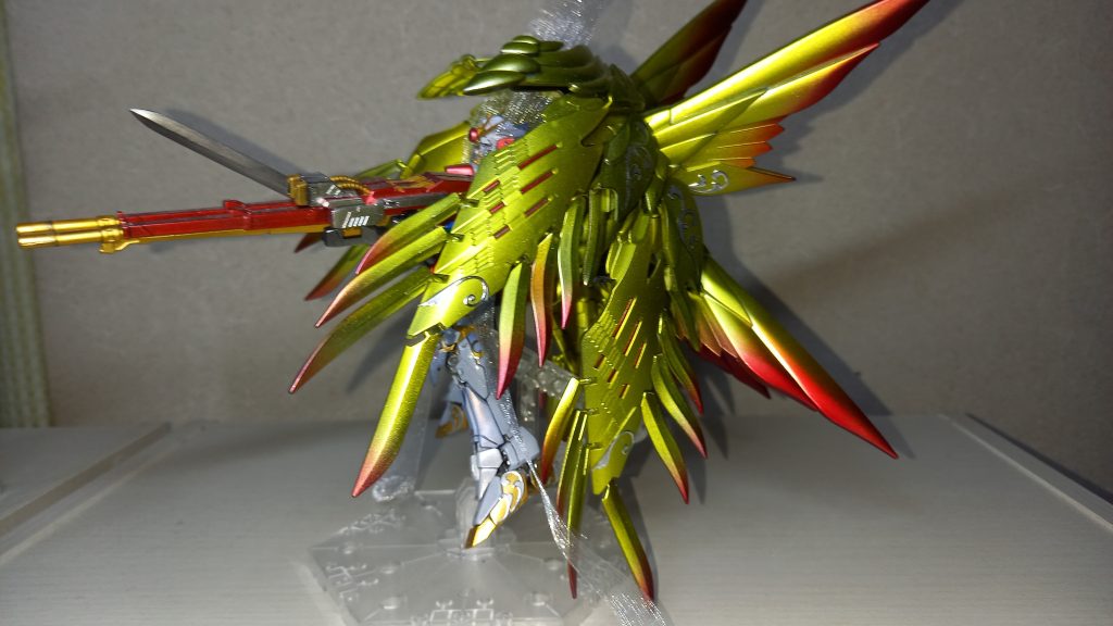 横からカラーリングはほとんど原形止めていませんカラーリング説明(すべてガイアノーツ)ほぼ全てのパーツを黒立ち上げ→各種シルバー→各々の色を重ね塗りしています羽はEXブラック→ハウンドシルバー→クリアイエロー→先端部分をクリアレッドでグラデ塗装初めてのグラデ塗装にしては自己満足しております足などの金はガイアノーツ・スターブライトゴールド、赤はパールプレミアムレッド、青はパールシルバーとウルトラブルー混色などなどあと、アドバンスドMSジョイントやハンドパーツはマルチプライマー吹き付けてからスターブライトシルバーや一部スターブライトゴールドマルチプライマーのおかげでやはりだいぶ強度が上がりましたが…この投稿用に腕動かしたら左肘間接がポキリと(T-T)