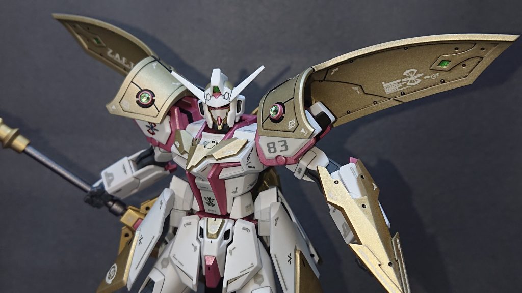 1番の拘りポイントは、肩回りに配置したアーマー兼マントの部分ですね💡これまでの騎士型ストライクに習って本機にもマントを取り付ける準備をしていたのですが、同じような布っぽいデザインのパーツだと少しマンネリ気味かなと思い行錯誤を繰り返した結果、このデザインに落ち着きました！RPG系のゲームに登場するキャラクターでたまにこのようなマントを付けていることがあったりしますよねｗ制作当初は肩に直接取り付けることを考えていたのですがパーツの形状的に難しく断念することになりました💦ですが、どうしてもこのパーツが欲しかったのでダブルオーガンダムを参考にし、バックパックからアーム接続で取り付けることにしました！装飾品として今回は100均で購入した“ライトストーンパーツ(黄緑)”を取り付けてみました！土台に“MSGプラユニット丸ノズル(S)”のサイズ4.0を使用しているのがポイントですねｗ高機動形態時にはマントが翼のように展開します！これにより肩回りの可動域が広がるので、より素早く攻撃的な動きが可能となります💡あと、見た目が格好良いですｗ✨