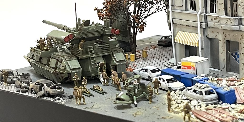 負傷兵でごった返す混沌とした状況を作ってみました。放置された自動車や青色のゴミ集積箱が市街地の雰囲気を出す良いアイテムになっています。道端に並べてある大きな青色のゴミ集積箱は日本の街並みでは見かけない物です。トラックの形状も日本の軽トラでは全くおかしな物になってしまうので軽ワゴンをあちらのトラックに改造してます。ジオラマに説得力を持たせる為にロケハンしてます（オデッサ市内をストリートビューで散策しました。）。このジオラマは6月に静岡市で開催される「そろてん」に展示する予定です。とても小さいなジオラマです…サイズ感を確認されたい方は是非ともお越しください😄