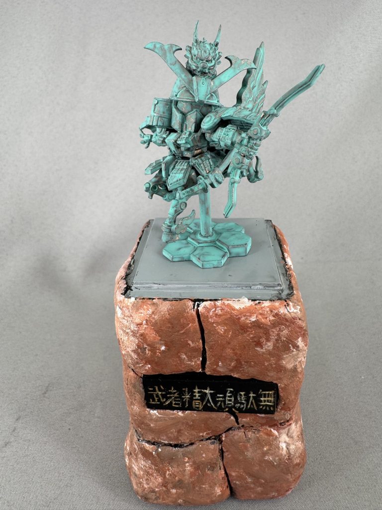 元のキットがディティールが細かく作られているので加工は一切せずそのまま作成。武者のガンダムということなので戦国武将の像っぽくしたら面白いかと思ったので銅像風に塗装しました。
