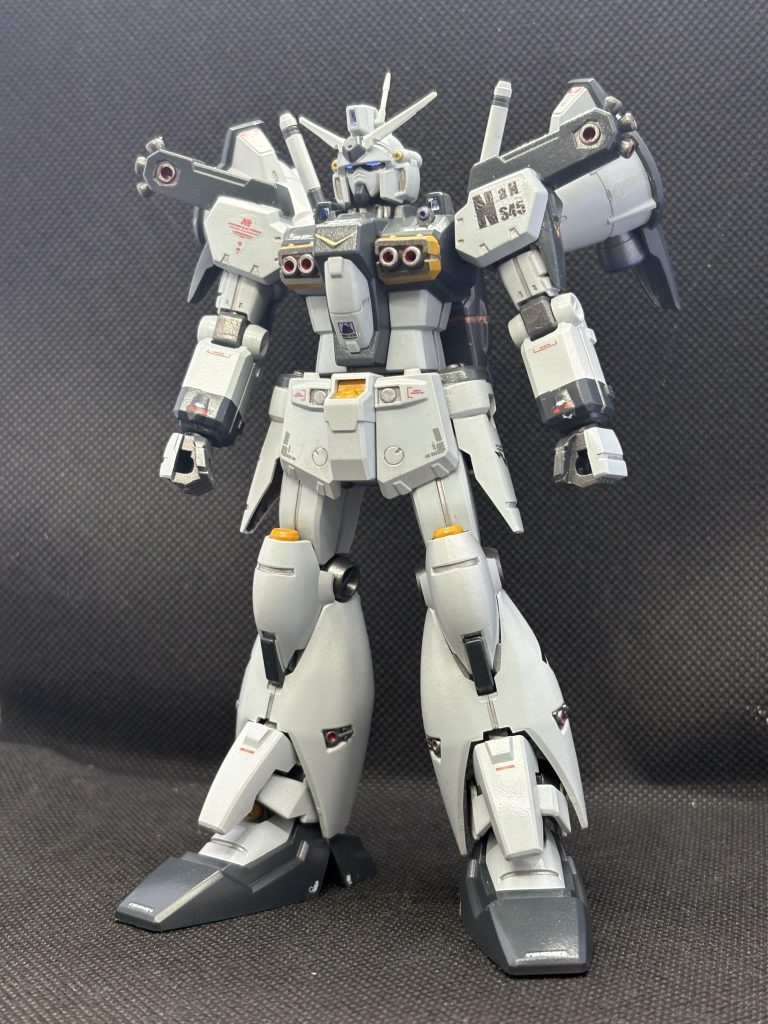 いつもの海軍風？配色です。肩のポリキャップをボールに替えています。ちょっとだけ可動範囲が良くなりますが保持力は下がりました。シールドをつけると結構厳しいかも。シールドは肩と干渉しないよう、穴を追加して取り付け位置を下げています。足裏の中央にどっかの余剰のバーニアとりつけていますが、写るアングルの写真撮ってませんでした。水転写式デカールは寄せ集めと余っている自作のやつ。関節やバーニアを避けて艶消し仕上げにしています。眼は金色の上に透明蛍光塗料。センサー類は水色のラピーテープをUVレジンで蓋しています。あとはバーニアっぽいところや頭部バルカンなどの穴あけくらいです。