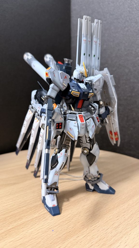 アムロの内側で、眠っていた光が揺らめく。νガンダムのサイコフレームに刻まれた“人の可能性を信じる力”。彼が最後に見た光——アクシズを押し返した、無数の人々の願いの結晶。「受け取れ。これは俺だけの力じゃない。人が未来へ進むための……道標だ」アムロの魂から金色の粒子がほとばしり、宇宙に散ったνガンダムの残滓を呼び寄せる。無数の光点が集まり、まるで記憶が逆流するように彼の周囲に現れた。それらの粒子はゆっくりとナラティブガンダムのフレームへと吸い込まれていく。未成熟なサイコフレームが共鳴し、青白い光が脈動し始めた。ヨナの胸に、言葉にならない温かさが広がった。失った少女の想い、仲間の願い、そして——見知らぬ誰かからの優しい力。「さあ……立ち上がれ。君にはまだ、やれることがある」アムロの声は風のようにヨナの魂に触れ、ナラティブは静かに輝きを増した。不完全だった器が、未来へ伸ばされた希望のように光を放つ。アムロは満足げに意識をほどいていく。もう導く必要はない。青年は自分の足で進むだろう。「未来は君たちのものだ……頼んだぞ」最後の言葉は音にもならぬまま、光の河へと溶けていった。そしてナラティブガンダムの胸奥には、νガンダムの魂と、アムロ・レイの静かな意志が確かに宿り続けた。