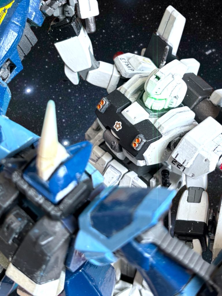 バーザムは、キャバルリーを引き離そうともがくが、その都度ヘントが組み付いていき離さない。実はインファイトはキャバルリーの十八番だが、今回の模擬戦はビームライフルの当たり判定だけが勝敗を決めるルールだ。2機は互いの、ライフルを持った右腕を押し合いながら、もがくように揉み合っている。こうしていればミヤギもバーザムを打ち抜けないが、ハイザックもヘントを打ち抜けないはずだ。 ミノフスキー粒子下の有視界戦を再現するため、粒子下で無効化されるレーダーやセンサーは切っている。互いの狙撃手は、見えないところまで後退してしまい、時々思い出したように威嚇じみた射撃をするだけだ。 観客のブーイングが聞こえてきそうな、地味な絵面だ。(何とかしなければ……。) ヘントは思考を巡らせる。 ミヤギの、今日の飛行は完璧だった。 狙撃もだ。 彼女の冴えこそが、最大の武器だ。(そうだ、そう——!)〜〜〜〜〜〜〜〜〜〜〜〜〜〜〜