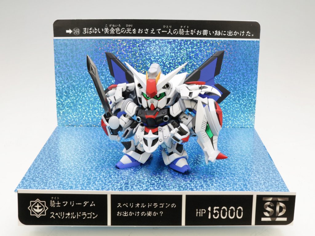 展示会用にカードダス風のスタンドを作成しました。当時のスペリオルドラゴンのカードダスを参考にメッセージを一部改変して世代の方が懐かしく思えるようにアレンジしました。カードの部分は実際のカードをLEGEND BBサイズに合うようExcel状で引き延ばして寸法を測って、似たような図形を作り出してメッセージ部分を改変して、コンビニのネットプリントで、A4光沢紙で印刷したものです。キラキラ背景は100均の推し活用うちわに貼るキラキラのデカいシールです。いろんな色があって、大きいし、安い