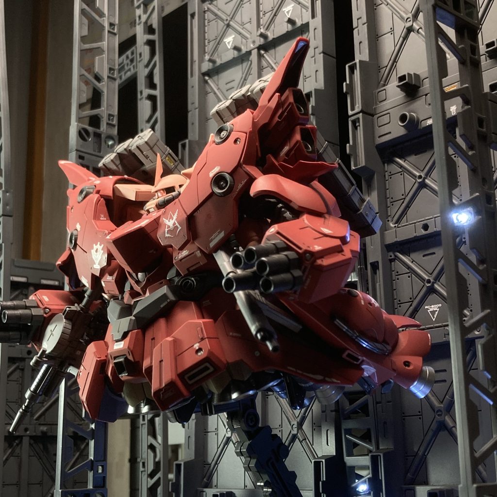 その後の「ジオング」の経緯・・・ その後しばらくして、建造が止まった状態の強化外殻「ジオング」は、フラガナン機関で研究が進められていたニュータイプ専用兵器サイコミュシステムを搭載したモビルスーツとして再び建造されることとなった。合わせて急速に実用化が進んだビーム兵器も搭載されることとなった。これらのために必要な機器や大型ジェネレーターを搭載することに、強化外殻としてザクを収納するはずだったスペースが空いていたのは、皮肉なことに好都合であった。また、新たに頭部と操縦席も追加された。かくして、ニュータイプ専用モビルスーツとして生まれ変わった「ジオング」であったが、ア・バオア・クーにてこの「赤」色ですらなくなった機体に搭乗したのが、結局はシャアだったことは運命の悪戯とでも言うべきものかも知れない。 時は流れて、宇宙世紀0096。ネオ・ジオン残党(いわゆる「袖付き」)は、「赤い彗星のシャアの再来」としてのフル・フロンタルに、その役割をより確かなものにすべく、シナンジュとその強化外殻を用意した。この強化外殻の設計ベースには、かつてのシャアのための強化外殻「ジオング」の設計図が用いられた。その狙いは容易に想像できるものの、入手経路については謎に包まれている(アナハイム社が絡んでいるとの噂はあるが、確認されてはいない)。かくして完成したシナンジュの強化外殻「ネオ・ジオング」はデザインこそ、かつての強化外殻「ジオング」を踏襲した部分が多く見られるものの、その大きさの違いはとてつもなく、全長100mを超える怪物であった。