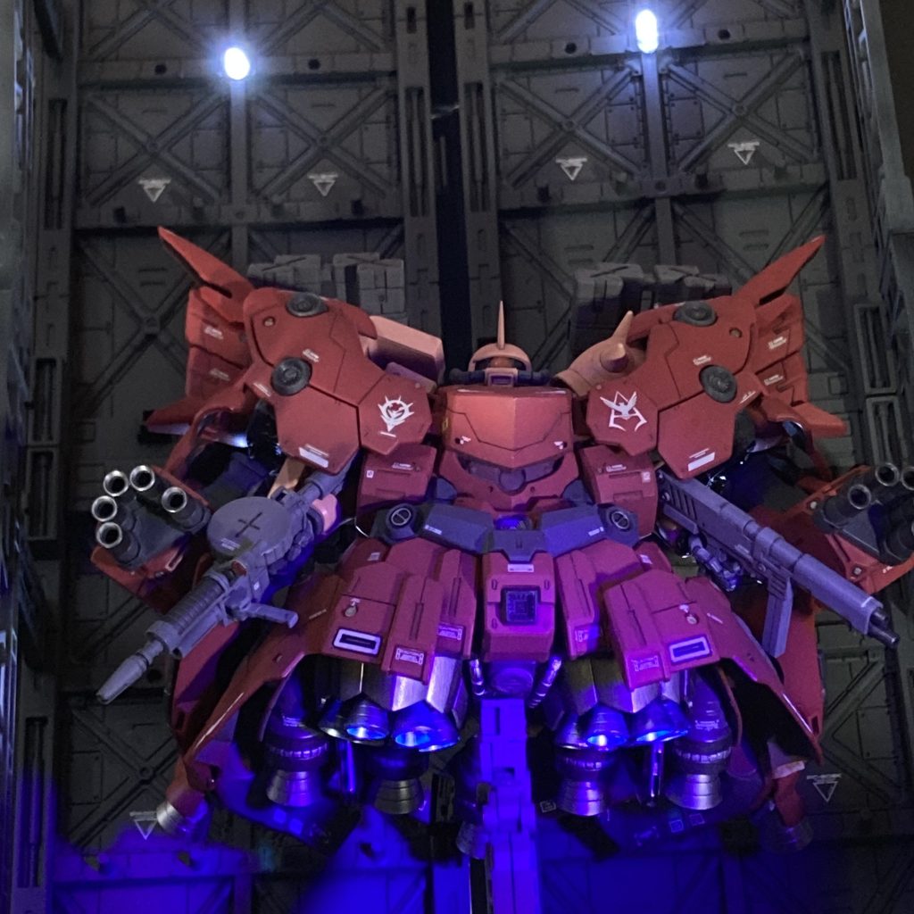 強化外殻「ジオング」の誕生・・・ 宇宙世紀0079、ルウム戦役で戦艦5隻を沈めたシャアの名は「赤い彗星」として急速に内外に広まっていた。このことを軍事的・政治的に利用しようと目論んだジオン軍は、シャアのザクの機動力、攻撃力をさらに押し上げるための専用強化外殻の開発に着手した。これは、ジオン国民に対してはの戦意高揚プロパガンダとして、そして地球連邦兵士に対しては恐怖心の醸成を狙ったものであった。かくして、その専用強化外殻はジオンの象徴として「ジオング」と名付けられ、設計は急速に進んだ。しかし・・・