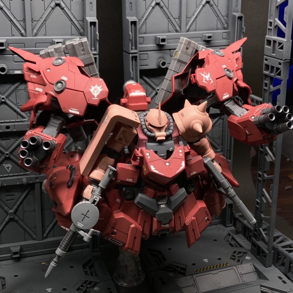 シャア専用ザクの格納・分離は、このように上部外殻を展開して行う。2種のマシンガンはスカート側面のラッチに固定されているように見えるが、実はザクの手が握っていることがこの写真からだとよく分かる。これは、被弾により外殻をパージするような緊急時、武器の持ち替えなしですぐ反撃できるようにとの、シャア自身の案によるもの。 ちなみに、格納されているザクは、当時、開発が進められていたザクの後期型(後にF2型と呼ばれる)をシャア専用にチューンナップしたものとなる予定であった。