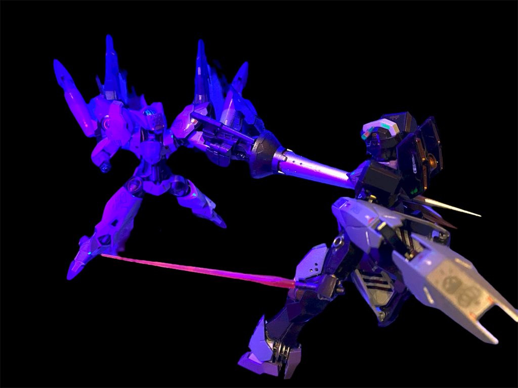 「勝者　　イエル・オルグ！！」 大歓声の中、コクピットから姿を見せたのは青紫のまとめ髪に目元を白い仮面で覆った青年であった。 「イエル・オグル……」ミオリネがその名を呟いた時、背後から聞き慣れた声の赤髪の大男が姿を現した。例の如く仮面でその顔を隠してはいたが、間違いなくそれはグエル・ジェタークのものであった。「あぁ。アイツの、、シャディク・ゼネリの元の名だ。」「グエル⁉︎ あっ、アンタ何やってるの！な、何でこんな所に？」 「シッ、あまり大きな声で目立つな。ドミニコス隊としての潜入捜査だ。1ヶ月前にセブンス・ヘブンが襲撃を受けた事件は知っているな？連合は公表していないが、実はあの時に収監されていたシャディクの身柄が拐われた。俺は今、奴の行方を追って此処にいる。」 「シャディクが⁉︎…一体誰がそんな事を？」「まだ分からないが、シャディクのかつての名を騙るあの男に、あの機体のさっきの赤い光…あれはGUNDフォーマットだった。この仮面武闘会…必ず何かあるはずだ！お前は……わかってる、分かってるよ。スレッタ・マーキュリーを探しに来たんだろ？」 2人がその会話を終えぬうちに、会場では早くも次の試合の組み合わせが発表されていた。 「それでは、いよいよ本戦の開始と致しましょう！1回戦Aブロック第一試合この舞台に立つのは、、、 荒々しき炎の蜥蜴、ダリルバルデ　ザラマンデルを駆るエントリーネーム・ボブ選手！対水に住まう麗しき氷の微笑、ファラクト　ウンディーネを駆るエントリーネーム・氷の君選手！」