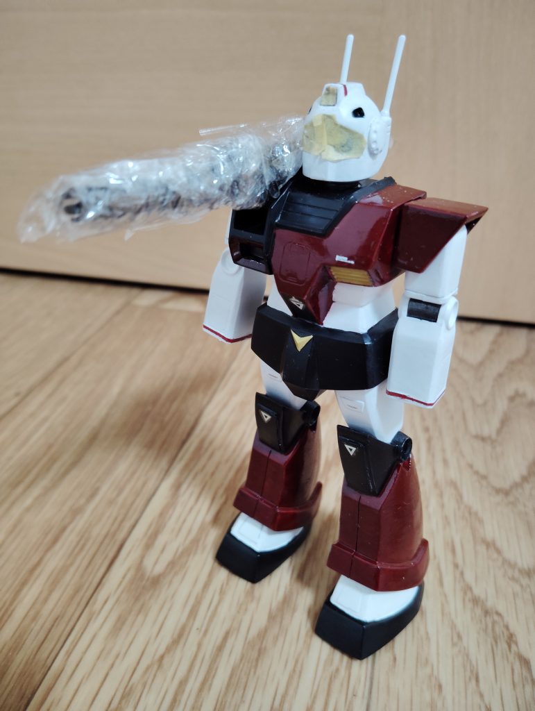 ツヤ消しトップコート前のマスキングです。 カメラ部分はともかく、せっかく金属っぽい光沢のある塗装ができたキャノン砲、マスキングテープでグルグル巻きにするよりも手っ取り早いのでは、と考え、台所にあったサランラップを巻いてマスキングしました。 これが予想以上に上手くいき、これからも使えそうな小ネタをひとつ発見できましたよ。 どうでもいいですが、この時点だと赤茶色の上からクリアーレッドを塗っただけの状態なので、赤色部分がまるでりんご飴みたいですね・・・。