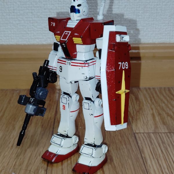 　ビームライフルのストーリー投稿第１７弾、そして最終回です。　ようやく完成しました！　勘の良い方なら分かっていたかもしれませんが、製作していたのはコチラ、初期試作型ビームライフルです。　銃身本体は銃鉄色（黒鉄色にツヤ有り黒を混ぜた色）、スコープや追加パーツのタンク的な部分などはミッドナイトブルー、銃身下部のエネルギーパック的なパーツや銃身両側の追加パーツ本体はニュートラルグレーにツヤ消し黒を混ぜた暗いグレーで塗装しました。　スコープは下地を銀色で塗装した上からクリアーブルーを塗ってあります。　塗装の参考にしたのは、神ゲ―だった前作の良い点を何ひとつ受け継ぐことができず、バグだらけでプレイ人口を減らしまくった挙句に大爆死したアーケードゲーム「戦場の絆Ⅱ」に登場する本武装です（改造工作も、コチラのゲームの画像を見ながら追加パーツなどを製作していきました）。　とりあえず手持ちのキットの中からこの武装が一番似合いそうな機体ということで、以前投稿したジム（リアルタイプカラー）に装備させてみました。　思ったよりもビームライフル自体が大型で、想像以上に似合っていて大満足です。　とはいえ、やはりこの武装が似合うのはただのジムではなく、コロニー落としの被害に遭ったあの地に配属された特殊部隊ですよね。　というワケで、この武装を装備する機体はこれから製作していきたいと思います。　なんとか2026年最新作として投稿できるよう頑張りますので、是非またのぞきに来てください。（4枚目）