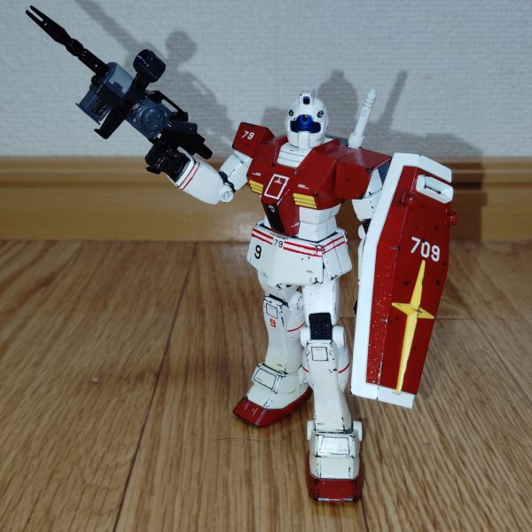 　ビームライフルのストーリー投稿第１７弾、そして最終回です。　ようやく完成しました！　勘の良い方なら分かっていたかもしれませんが、製作していたのはコチラ、初期試作型ビームライフルです。　銃身本体は銃鉄色（黒鉄色にツヤ有り黒を混ぜた色）、スコープや追加パーツのタンク的な部分などはミッドナイトブルー、銃身下部のエネルギーパック的なパーツや銃身両側の追加パーツ本体はニュートラルグレーにツヤ消し黒を混ぜた暗いグレーで塗装しました。　スコープは下地を銀色で塗装した上からクリアーブルーを塗ってあります。　塗装の参考にしたのは、神ゲ―だった前作の良い点を何ひとつ受け継ぐことができず、バグだらけでプレイ人口を減らしまくった挙句に大爆死したアーケードゲーム「戦場の絆Ⅱ」に登場する本武装です（改造工作も、コチラのゲームの画像を見ながら追加パーツなどを製作していきました）。　とりあえず手持ちのキットの中からこの武装が一番似合いそうな機体ということで、以前投稿したジム（リアルタイプカラー）に装備させてみました。　思ったよりもビームライフル自体が大型で、想像以上に似合っていて大満足です。　とはいえ、やはりこの武装が似合うのはただのジムではなく、コロニー落としの被害に遭ったあの地に配属された特殊部隊ですよね。　というワケで、この武装を装備する機体はこれから製作していきたいと思います。　なんとか2026年最新作として投稿できるよう頑張りますので、是非またのぞきに来てください。（5枚目）